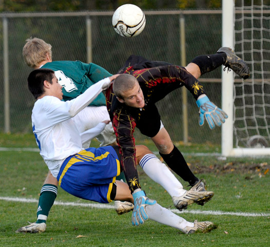 Homestead's Cordero Magana, in white, collides with Northridge goalkeeper Derrick Giddens, right, and Northridge's Andrew Jones, in green, as the three players battle for the ball during second period action in Homestead's 2-1 victory over Northridge in the Boys Soccer Semi-State at Hefner Field Monday night.
