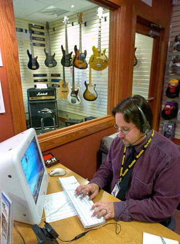 Sweetwater Sound sales engineer Brian Conn takes a phone order from a  customer while working in the showroom. Behind him is part of the showroom's  bass guitar selection.